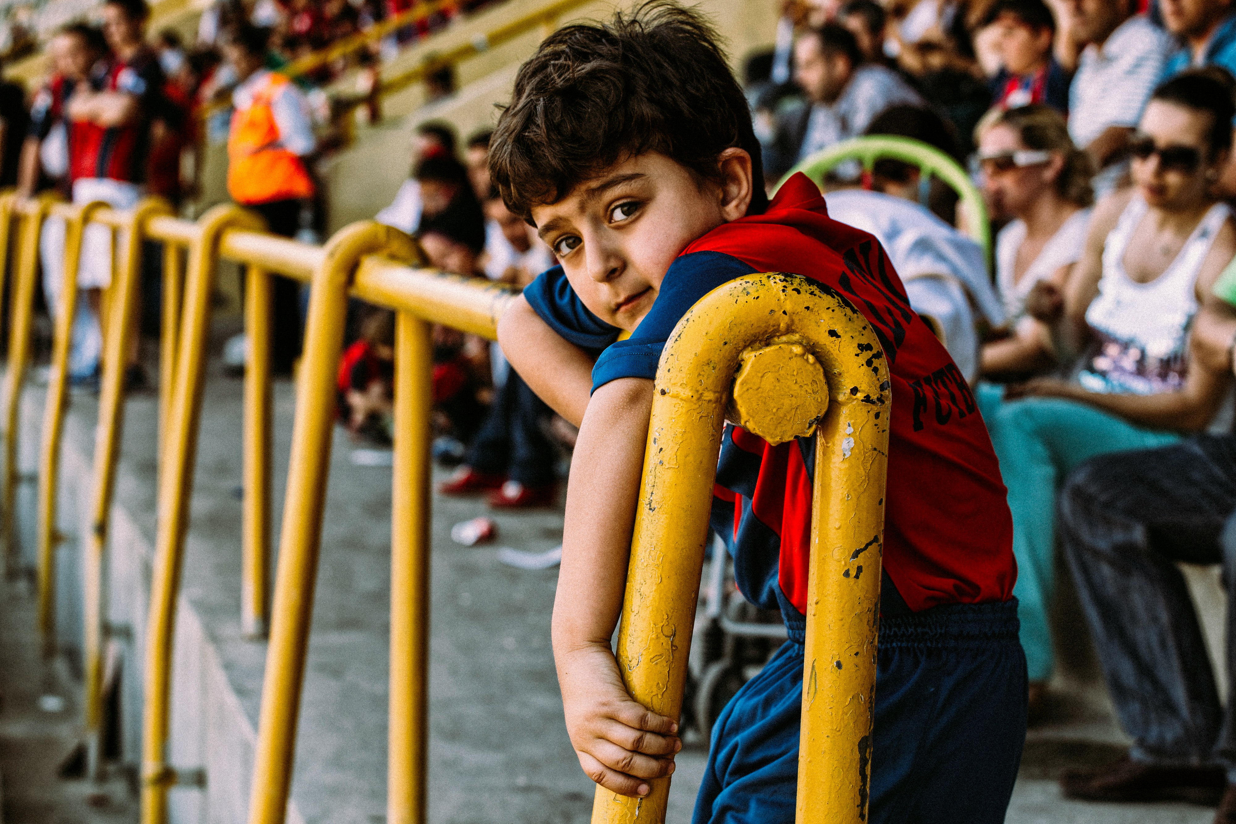 boy in blue and red shirt holding yellow metal bar